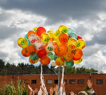 Two large clusters of multicolored helium balloons with hands reaching up, illustrating an article about learning to release what no longer serves you.
