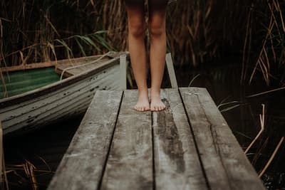 Lower legs of a young person on a rustic looking dock illustrating the concept that Post-Traumatic Stress Disorder (PTSD) occurs when a person has been exposed to actual or threatened serious harm