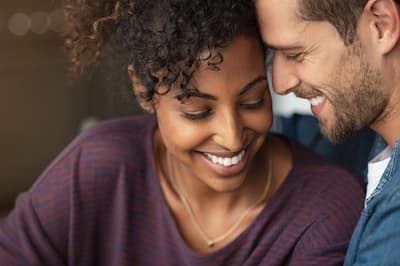 Close up of interracial couple with heads together, illustrating the concept that Couple's and Partner therapy can be a path forward to creating a healthy relationship.