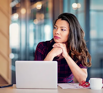 Black young woman sitting in front of a laptop looking off in the distance illustrating article about mindless habits
