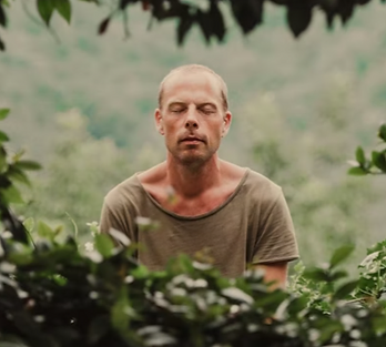 Middle aged Caucasian man meditating amongst bushes illustrating article about ways to calm down